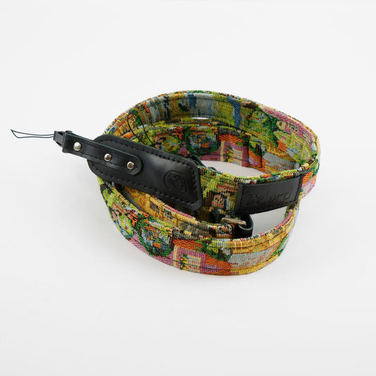 A fabric camera strap featuring a colorful, multicolor landscape pattern with green, yellow, orange, and blue tones, finished with black leather hardware and a black brand tag that reads 'Felard'.