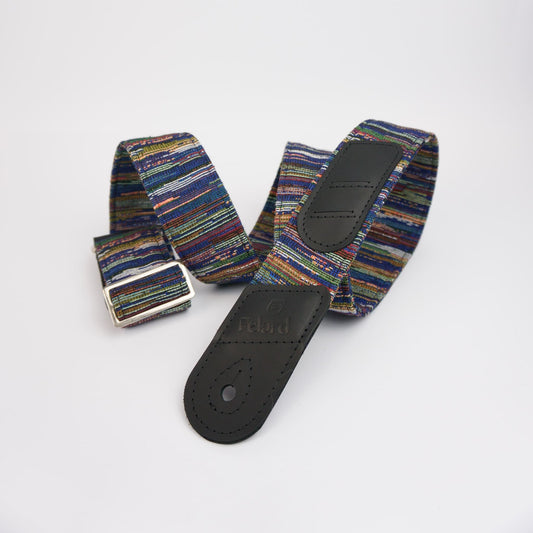A multicolor striped canvas guitar strap with black leather end pieces and a silver metal buckle, displayed on a clean white background.
