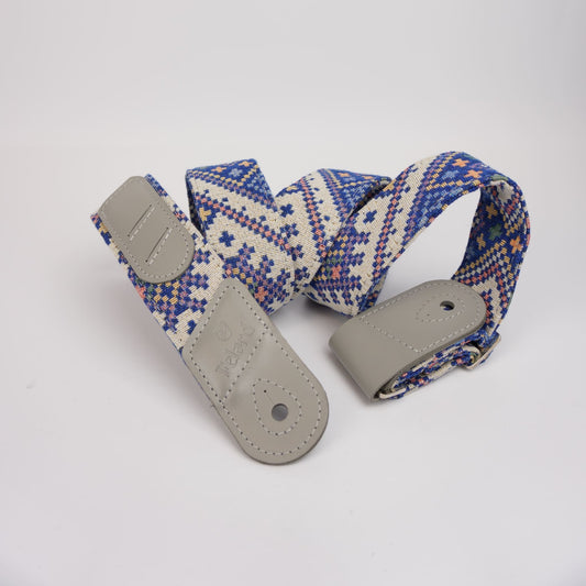 guitar strap with a blue, white, and orange geometric pattern and gray leather ends, displayed on a clean white background.