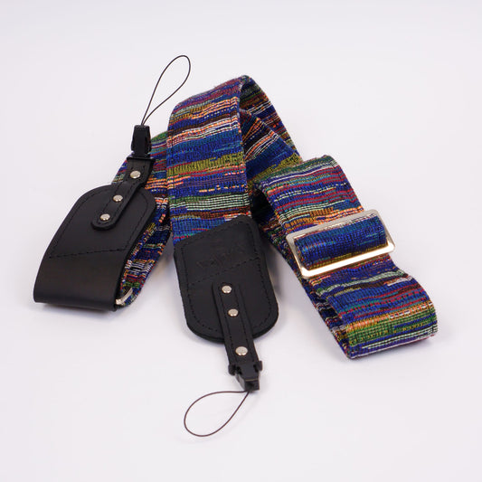 A multicolor camera strap with black leather ends and silver metal buckle, displayed on a clean white background.