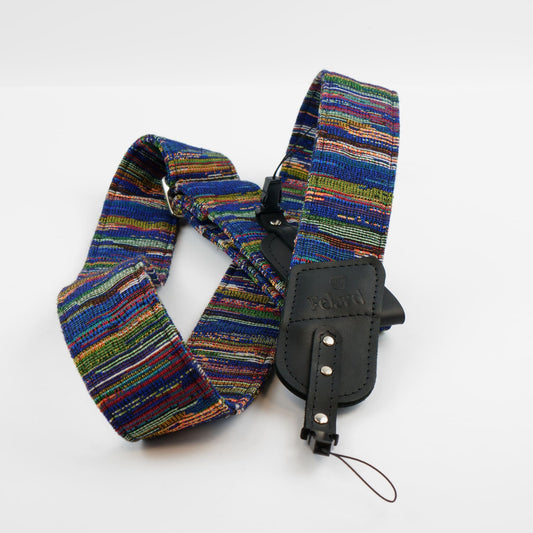 A multicolor woven camera strap with a black leather displayed on a clean white background.