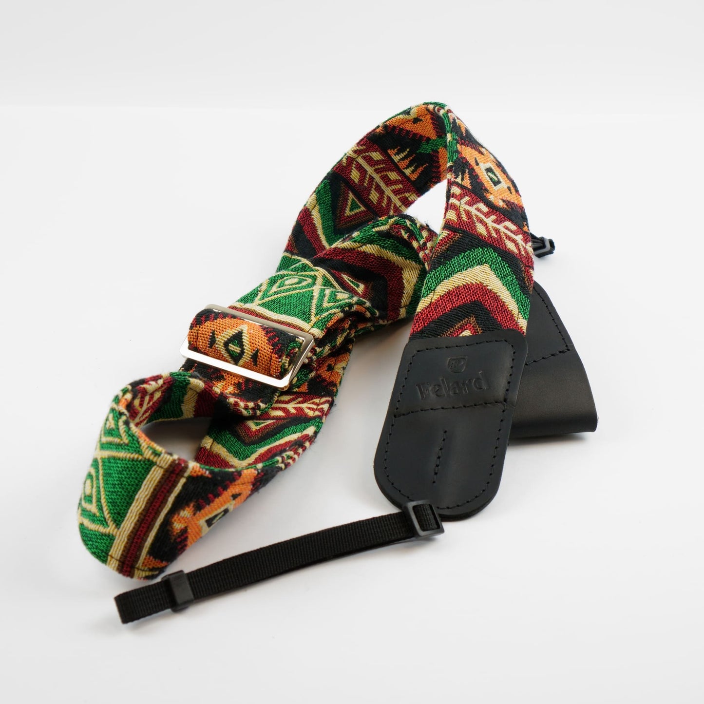 A woven camera strap with a Southwestern geometric pattern in green, orange, brown, and black, featuring a black leather.