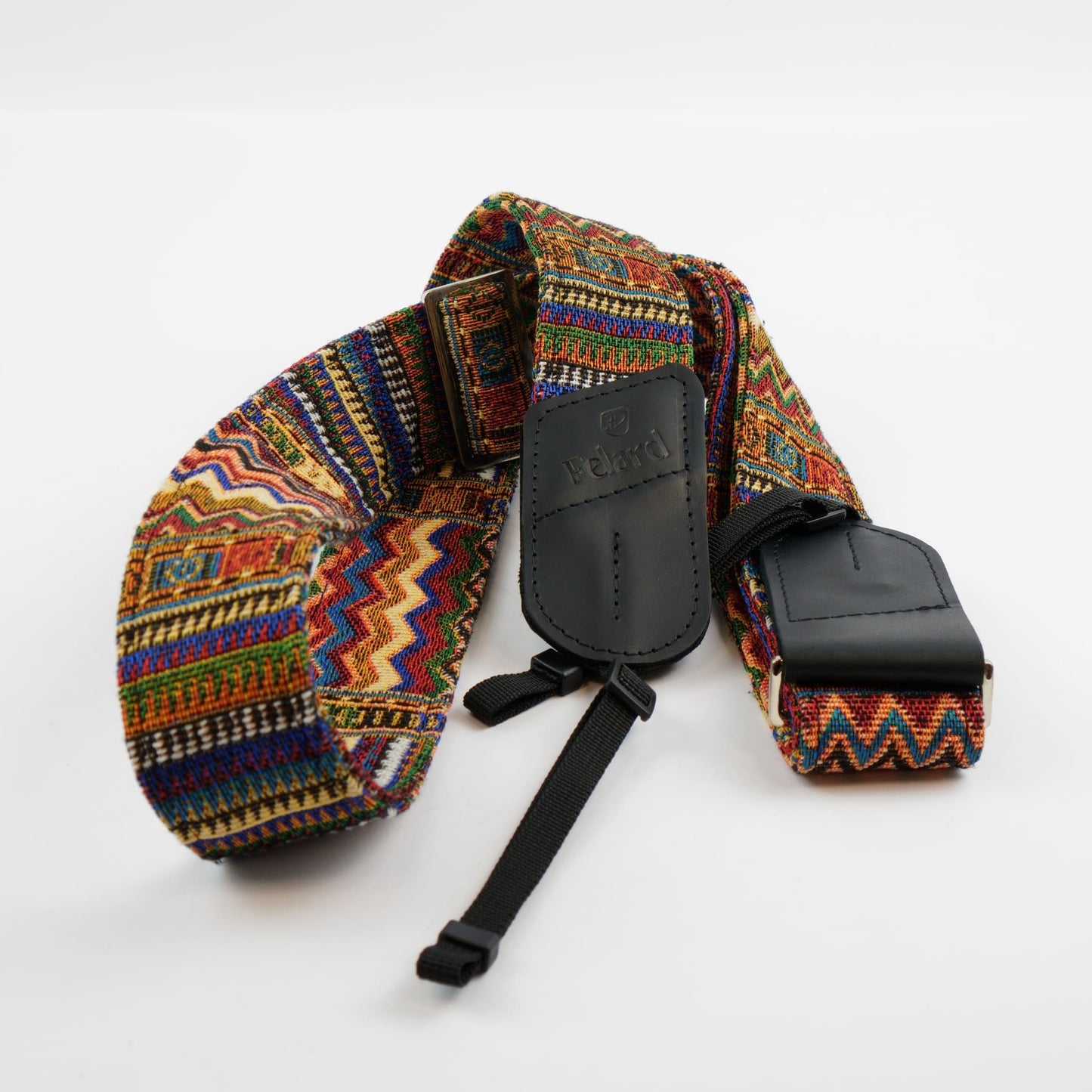 A multicolor woven camera strap with a geometric pattern, featuring black leather accents and a black plastic buckle, displayed on a clean white background.