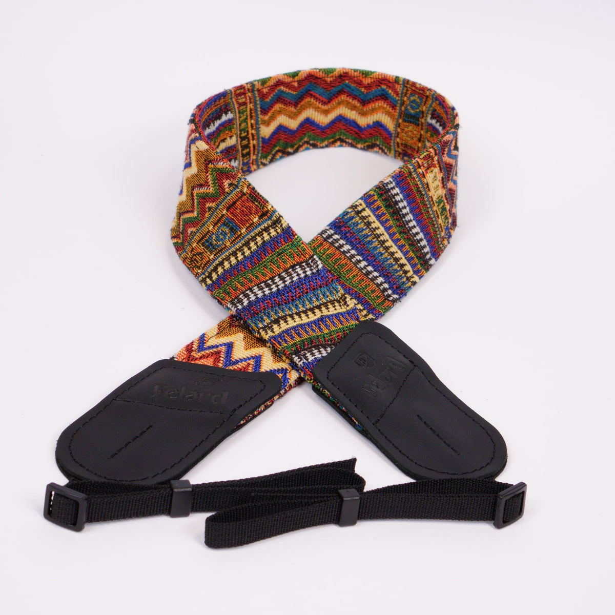A woven camera strap with a vibrant multicolor geometric pattern, featuring black leather ends displayed on a clean white background.