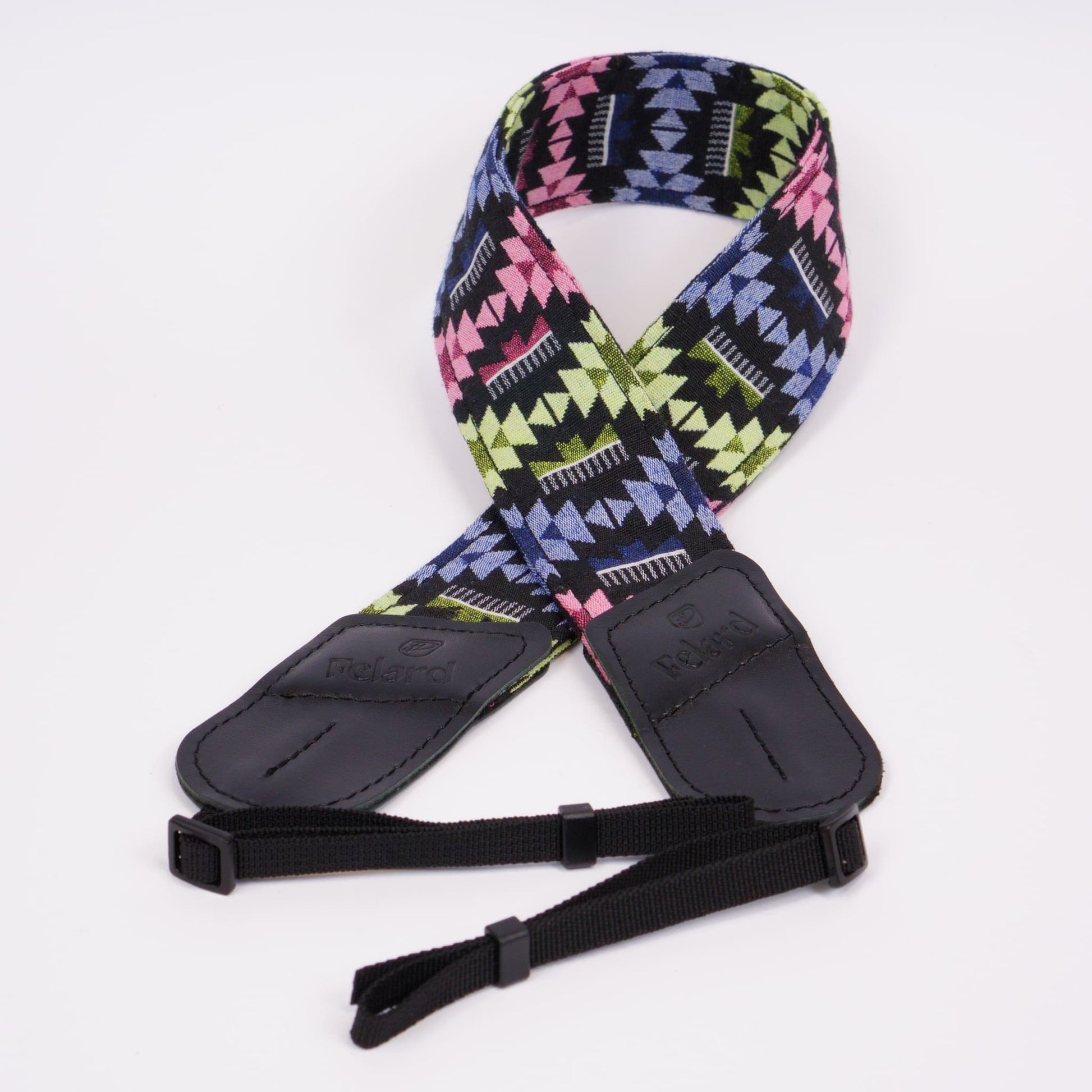 A camera strap featuring a vibrant geometric pattern in pink, lime green, blue, and black, with black leather ends and adjustable black webbing.
