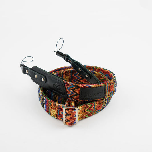 A woven belt with a vibrant multicolor geometric pattern, featuring black leather accents and a silver-tone metal buckle, displayed on a clean white background.