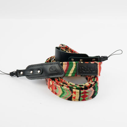 A camera strap with a colorful geometric pattern in red, green, yellow, and black, featuring black leather accents and a visible 'Felard' logo patch.