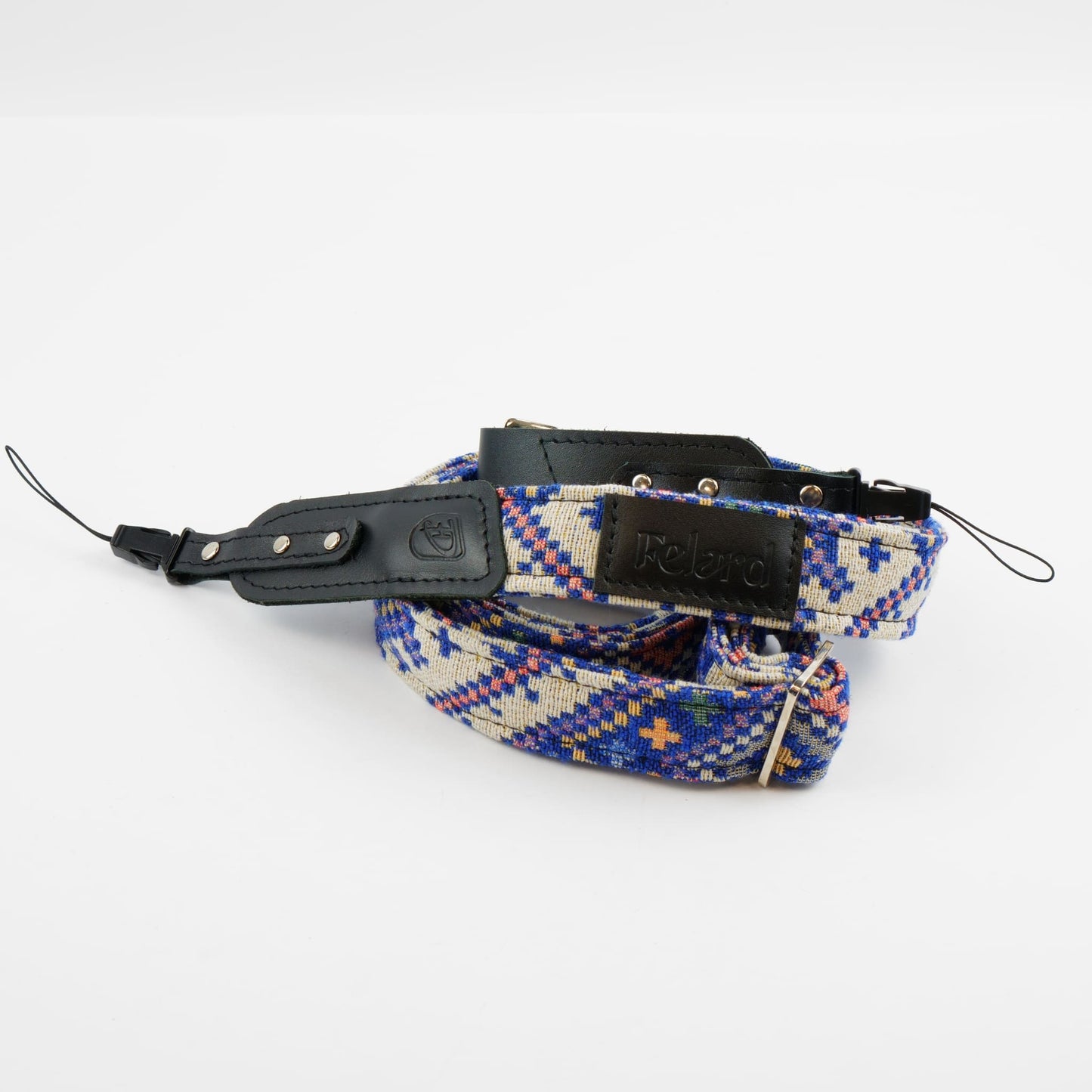 A Felard brand camera strap featuring a blue, red, and beige geometric patterned woven fabric with black leather accents and silver metal hardware, displayed on a clean white background.
