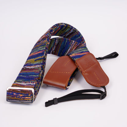 A multicolor camera strap with brown leather ends and black adjustment straps, displayed on a clean white background.