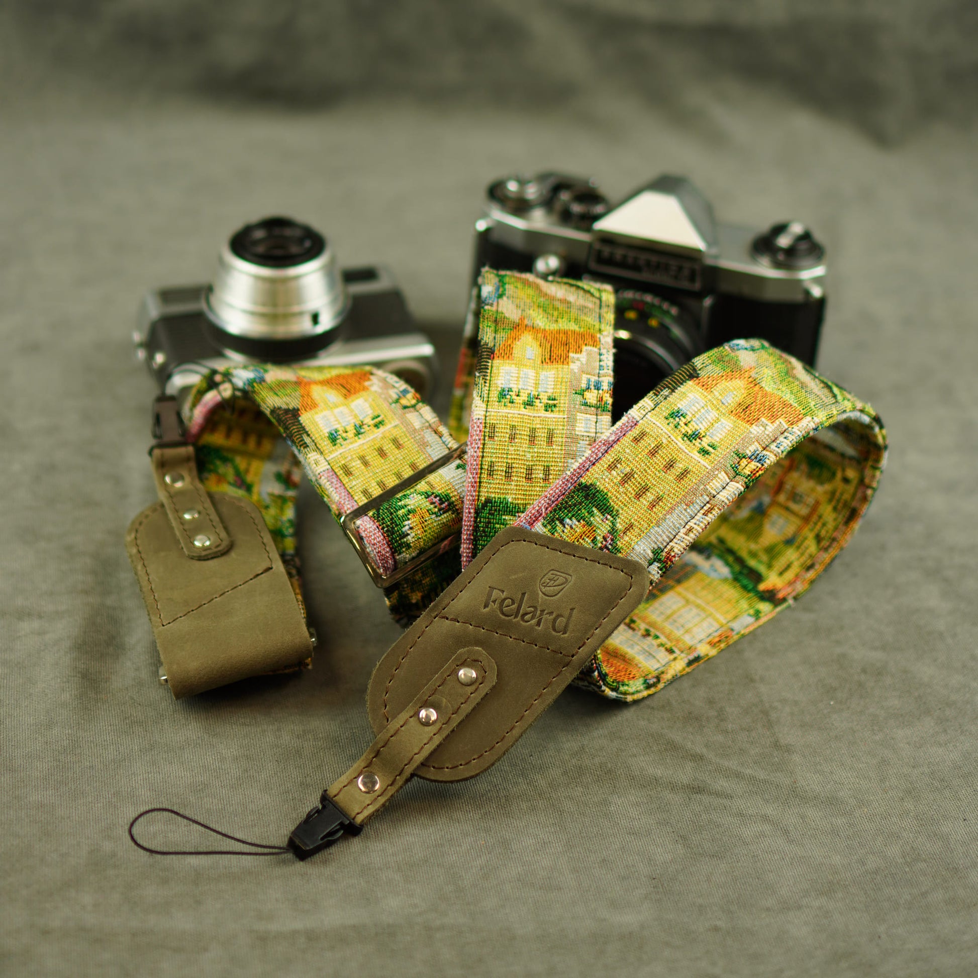 A vintage camera strap with a colorful architectural print in yellow, green, and pink