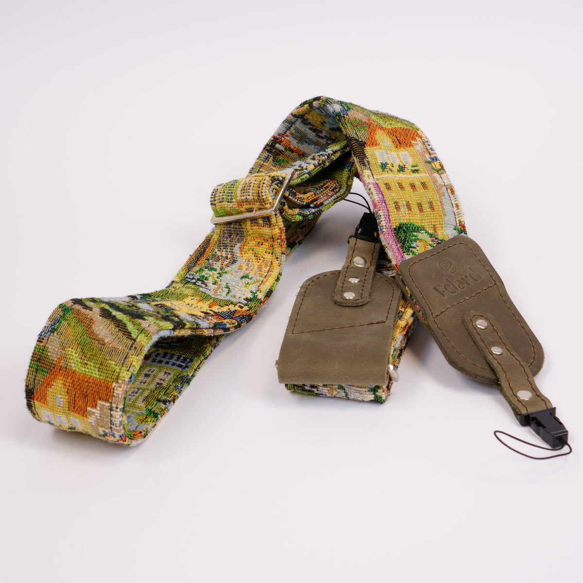 A camera strap featuring a colorful landscape patterned fabric and gray leather accents, displayed on a clean white background.