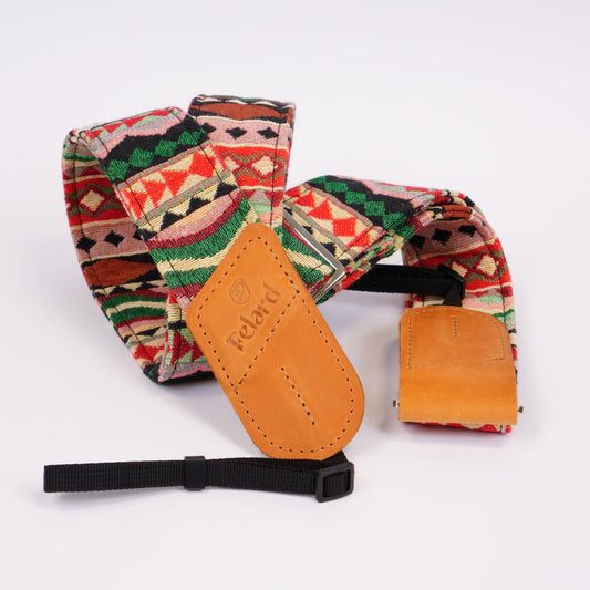 A camera strap featuring a colorful Southwestern geometric patterned fabric and tan leather accents, displayed on a clean white background.