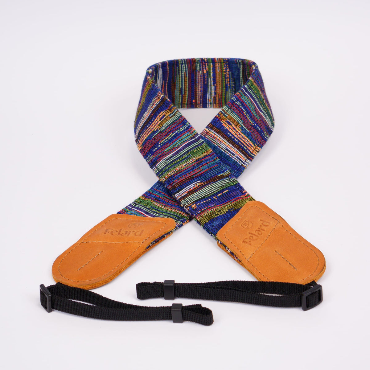 A multicolor camera strap with tan leather ends and black adjustable webbing, laid flat on a white background. The brand name 'Felard' is embossed on the leather ends.