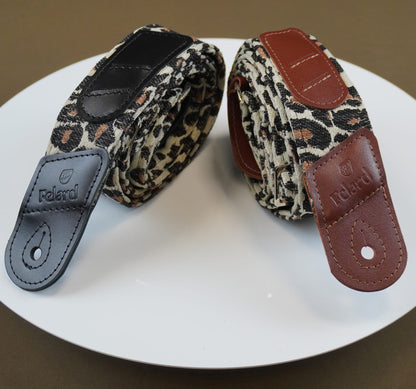 Felard guitar straps with leopard print fabric and leather accents, displayed on a white plate against a brown background.