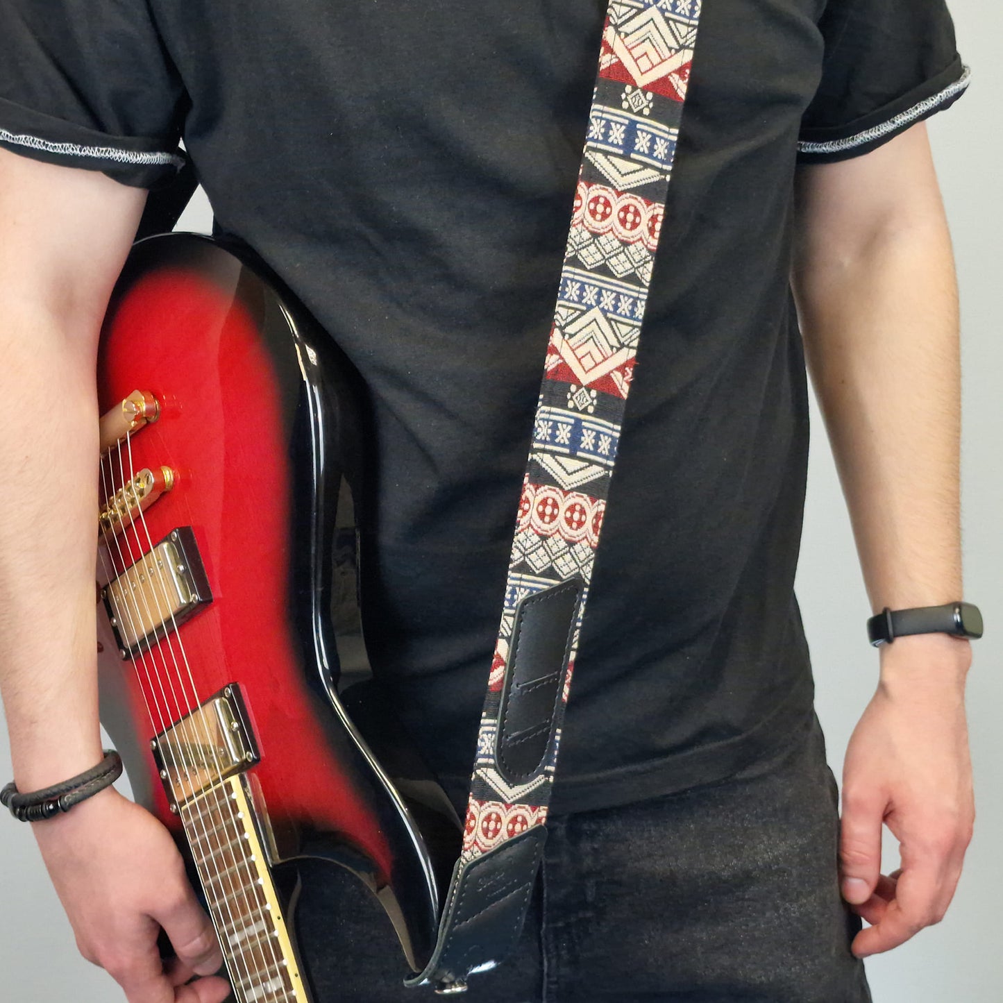 patterned guitar strap with geometric designs in red, blue, white, and black.