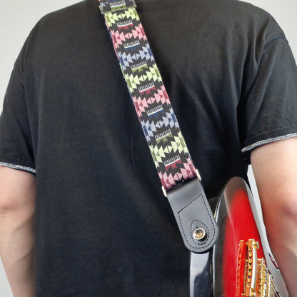 colorful patterned guitar strap with a black leather end piece.