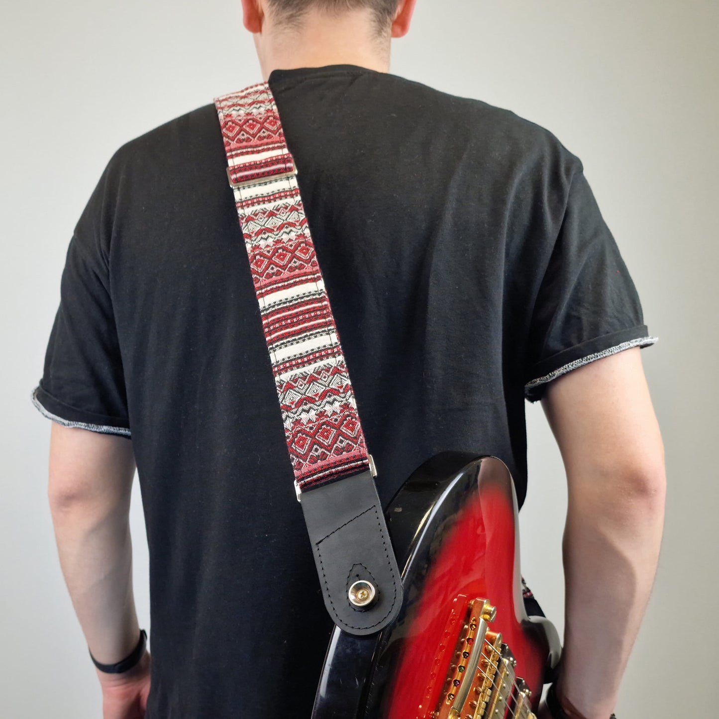  black guitar strap with a gold snap button.