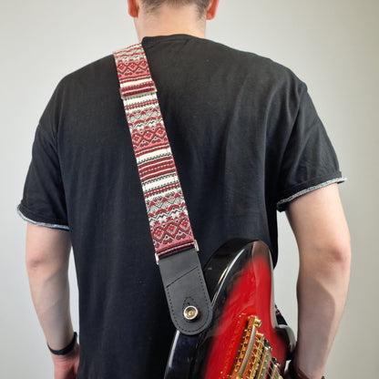  black guitar strap with a gold snap button.