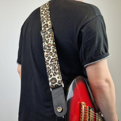  leopard-print fabric shoulder strap with black leather ends and gold-tone metal hardware.