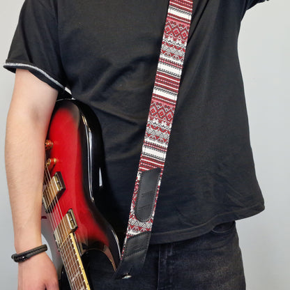  patterned guitar strap with a red, white, and black geometric design.