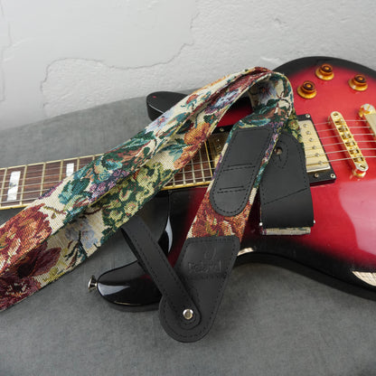 A floral patterned electric guitar strap with black leather ends