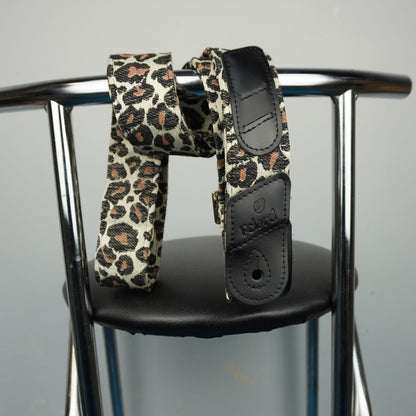 A leopard print waist strap with black faux leather accents, draped over the armrests of a chrome chair.