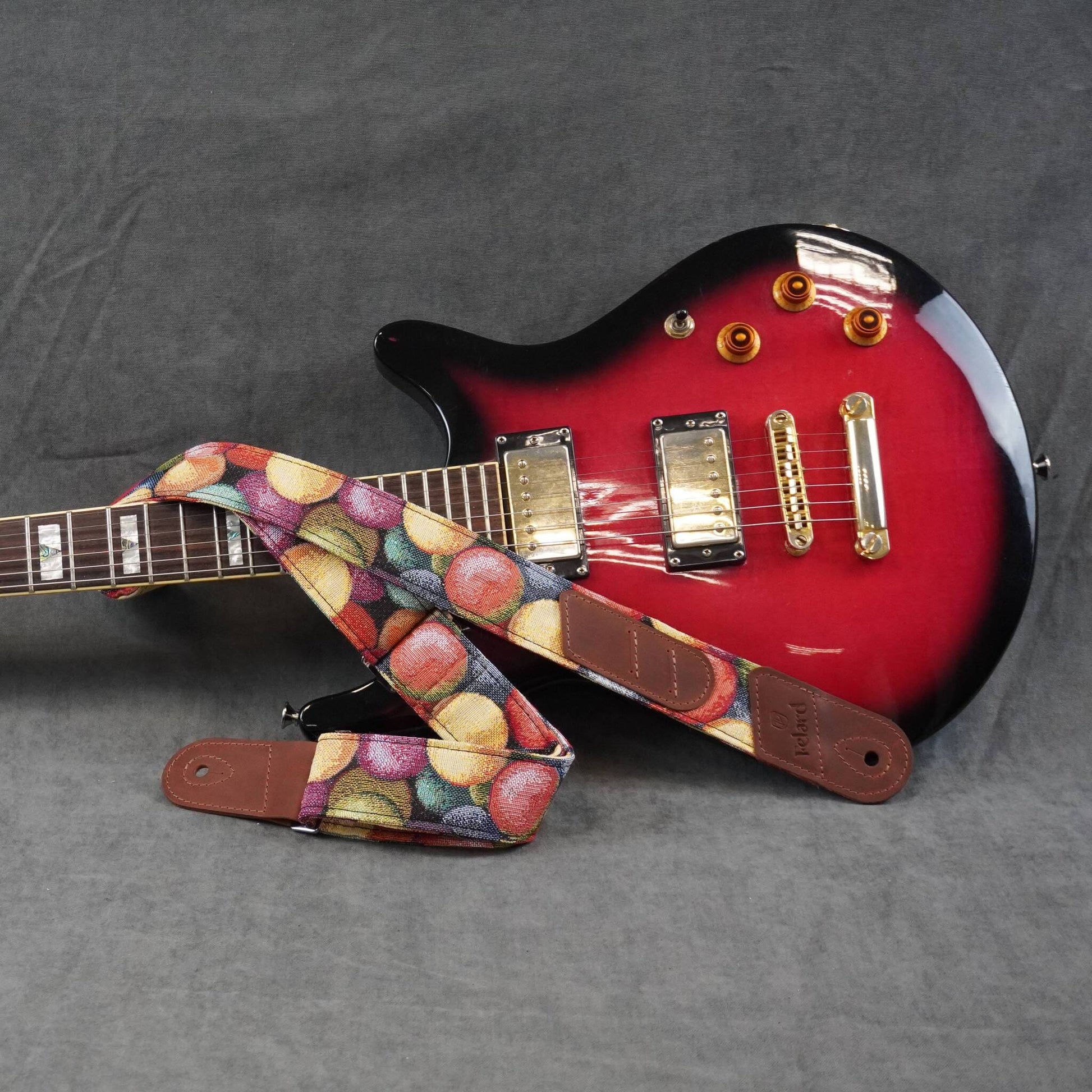 guitar strap, displayed on a textured gray background.