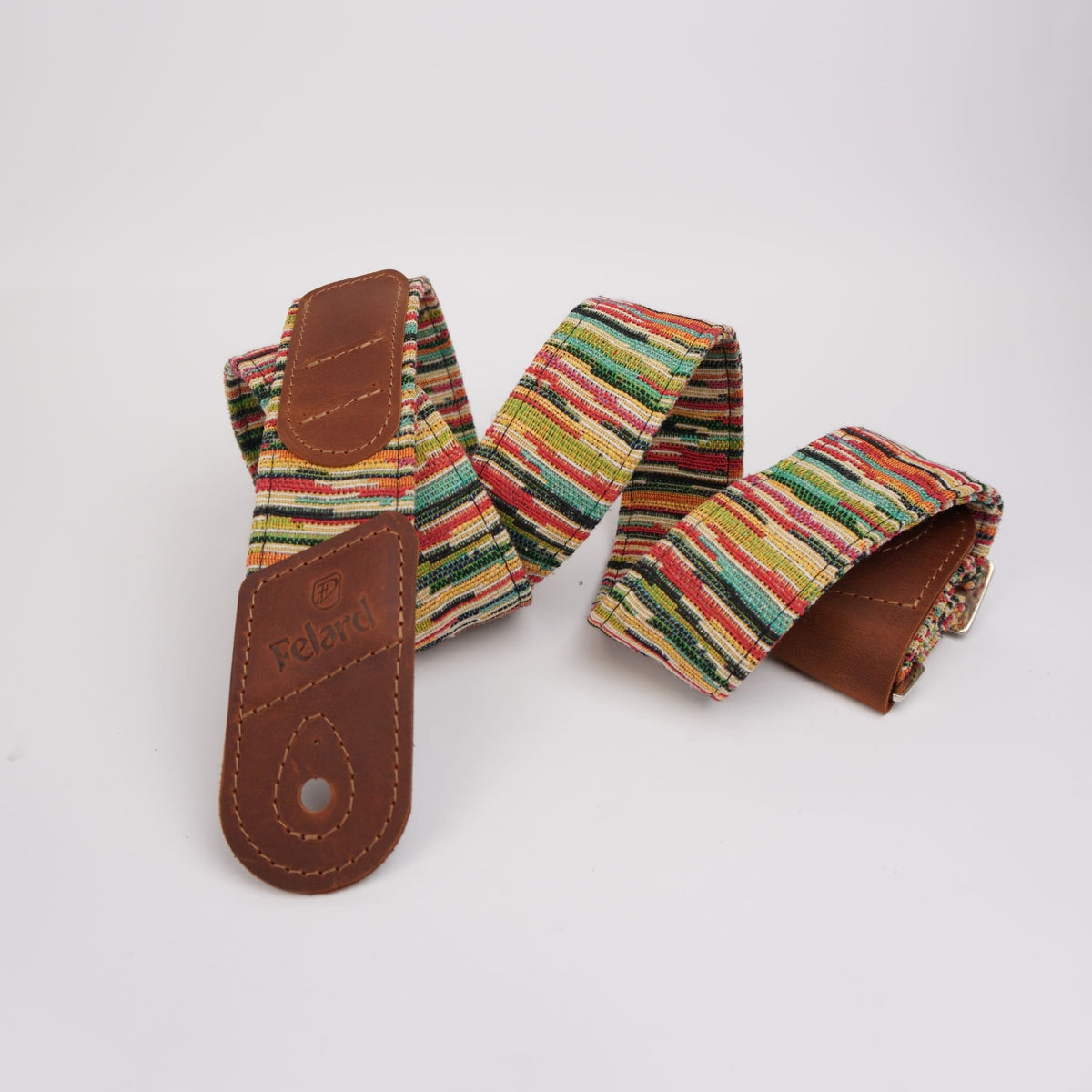 Colorful striped guitar strap with brown leather ends, one of which is embossed with the brand name 'Felard'.