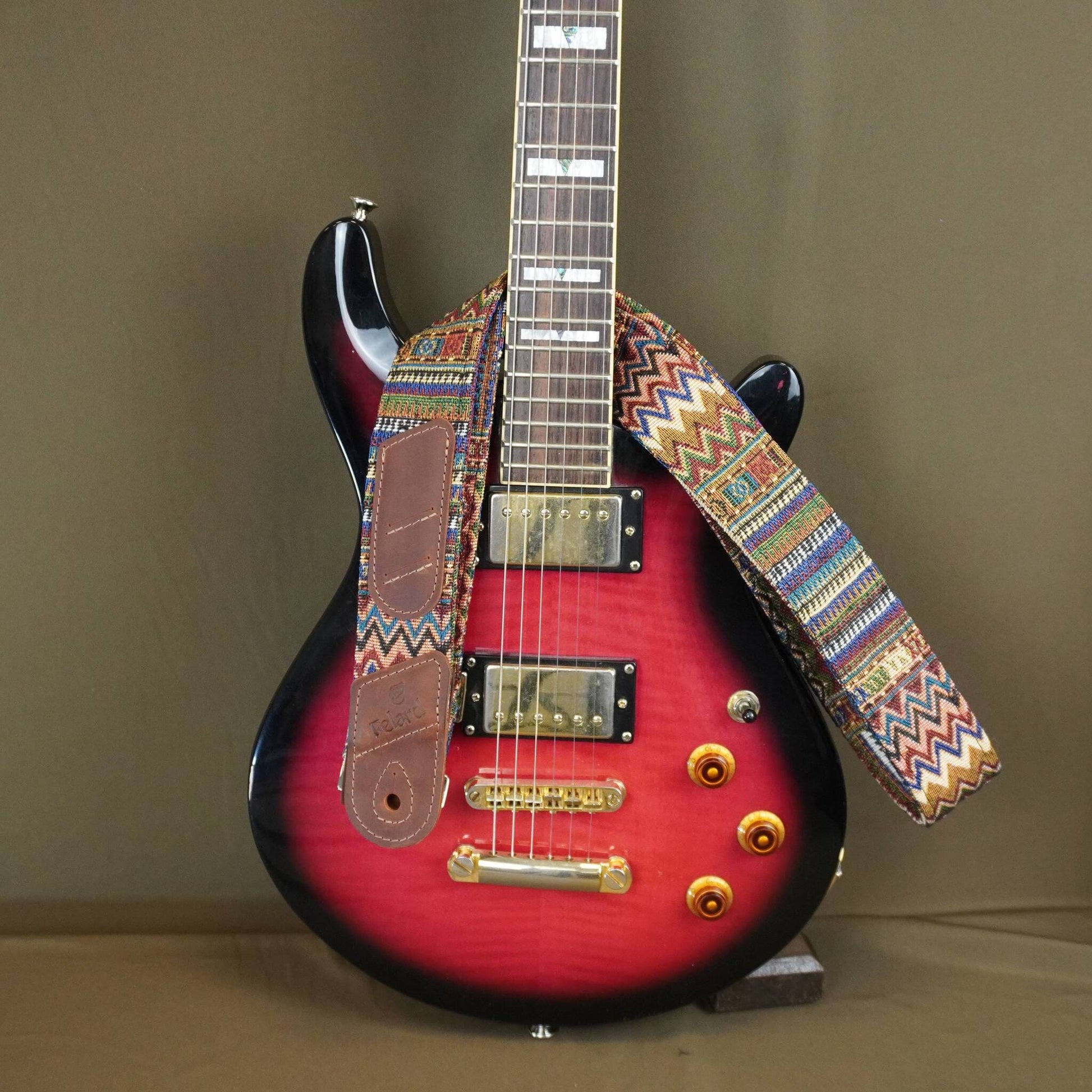 colorful patterned strap, displayed on a stand against a plain brown background.