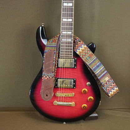 colorful patterned strap, displayed on a stand against a plain brown background.