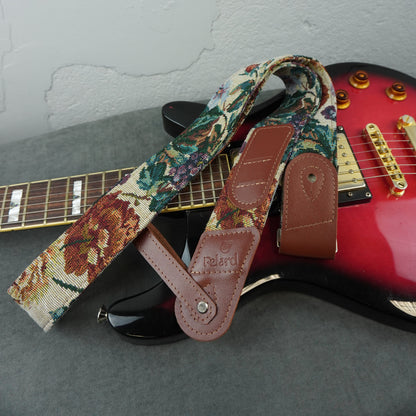 A floral tapestry-style electric guitar strap with brown leather end pieces
