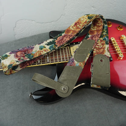 A floral tapestry-style electric guitar strap with gray leather end pieces