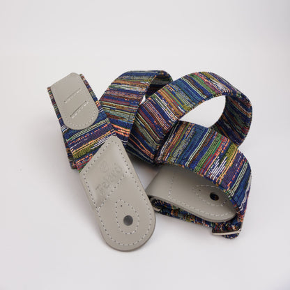 A multicolor striped guitar strap with light gray leather ends, shown on a clean white background.