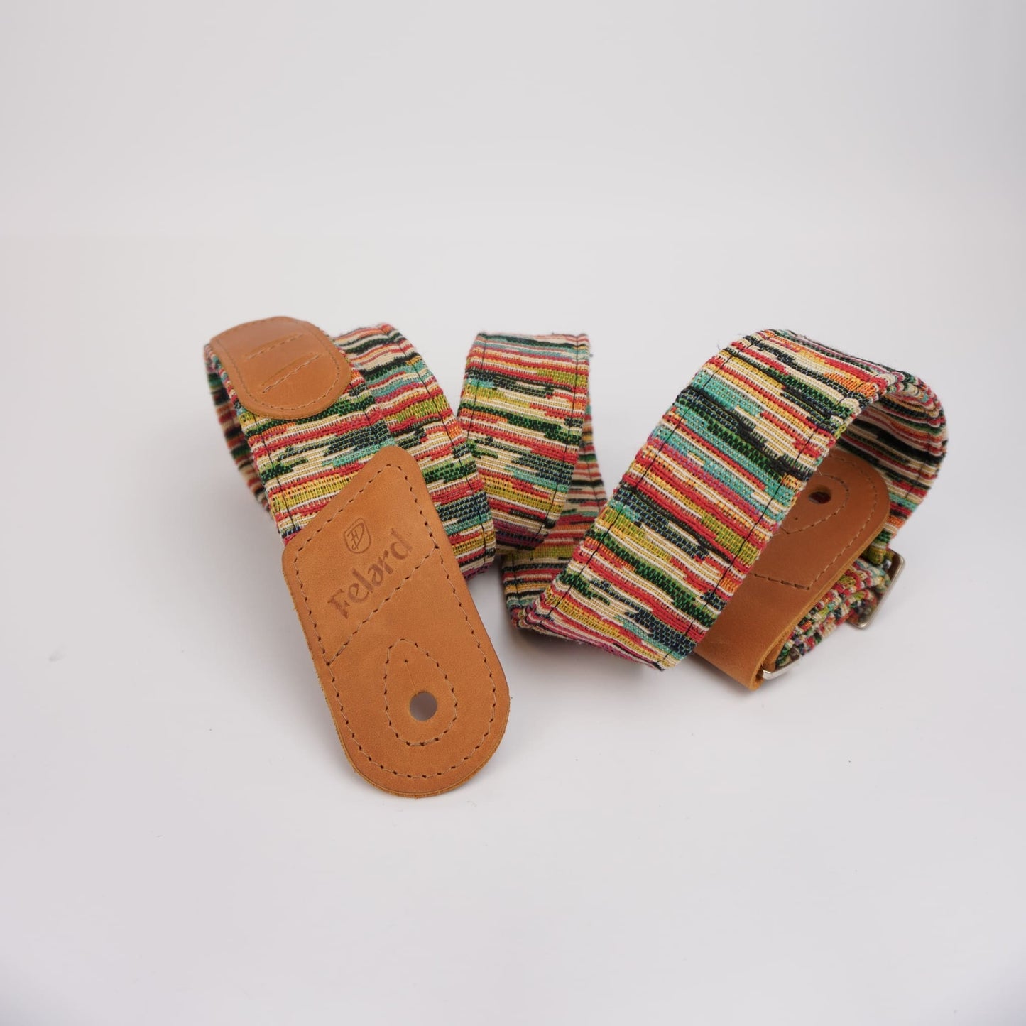 Colorful striped guitar strap with tan leather ends, one of which is embossed with the brand name 'Rolan'.