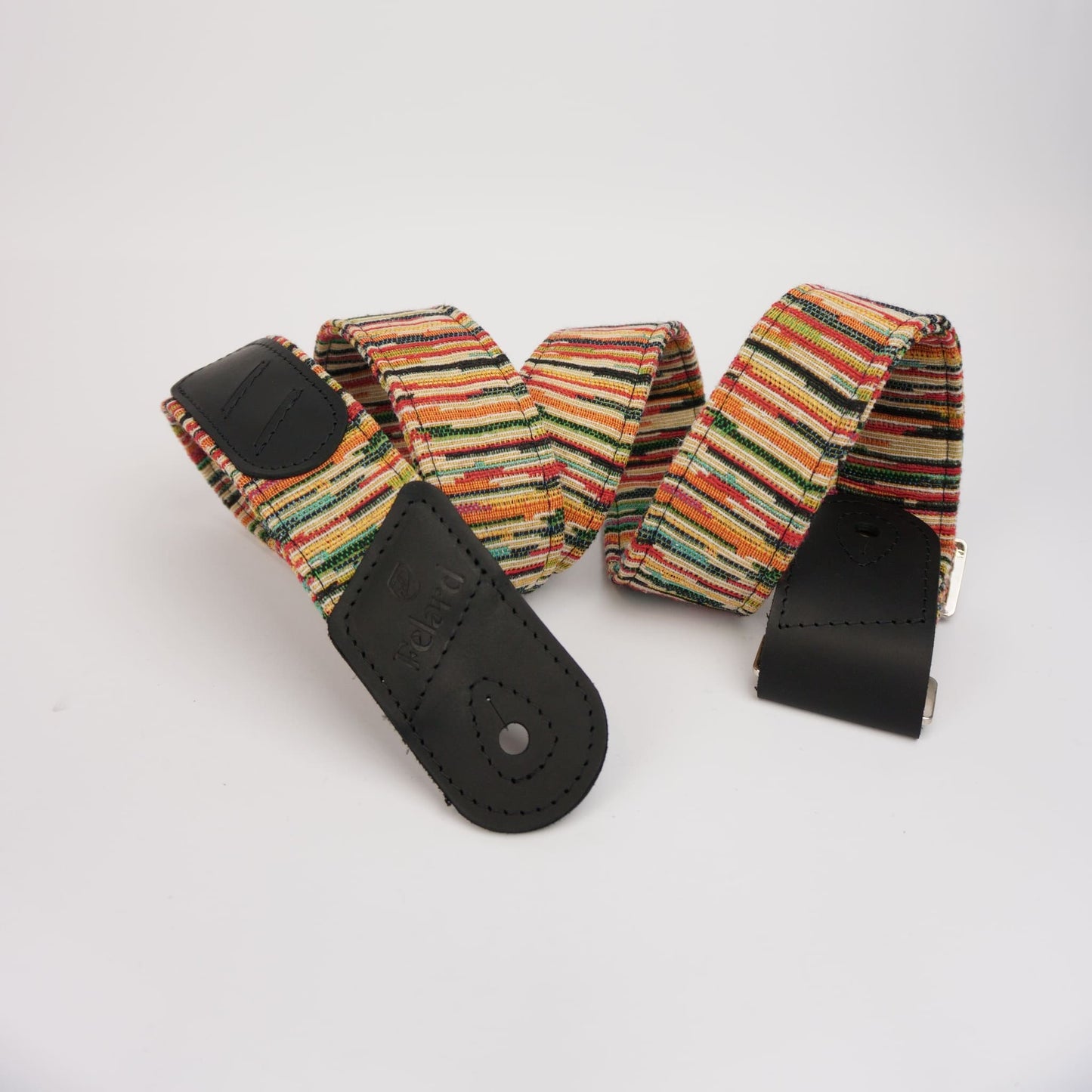 A woven guitar strap with a multicolor striped pattern of orange, green, yellow, and red, featuring black leather end-caps and a silver metal buckle, displayed on a clean white background.