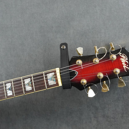 A close-up of a guitar headstock adapter from black matte leather
