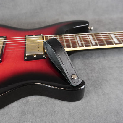 A close-up of an electric guitar with a black smooth leather guitar headstock adapter