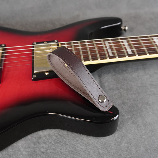 A close-up of an electric guitar with a dark brown smooth leather guitar headstock adapter