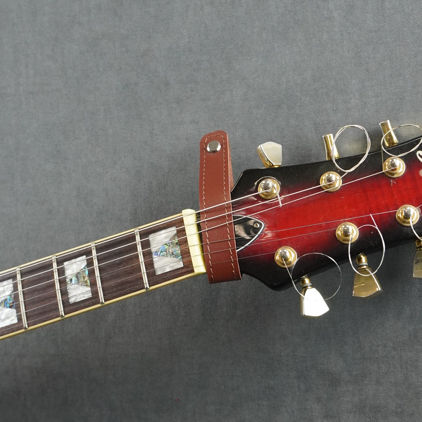 A close-up of a guitar headstock adapter from cognac smooth leather