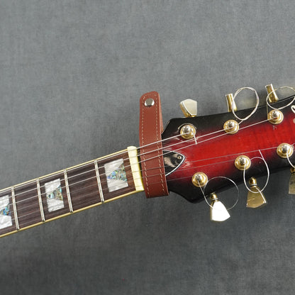 A close-up of a guitar headstock adapter from cognac smooth leather