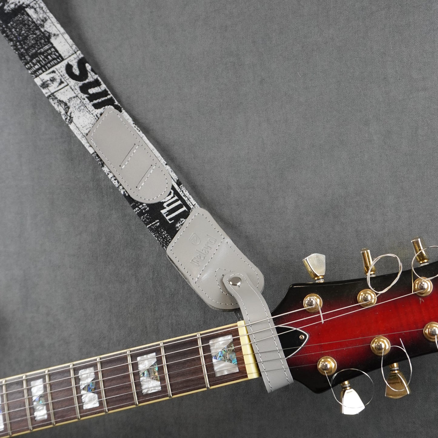 A guitar strap with fabric with gray smooth leather headstock adapter