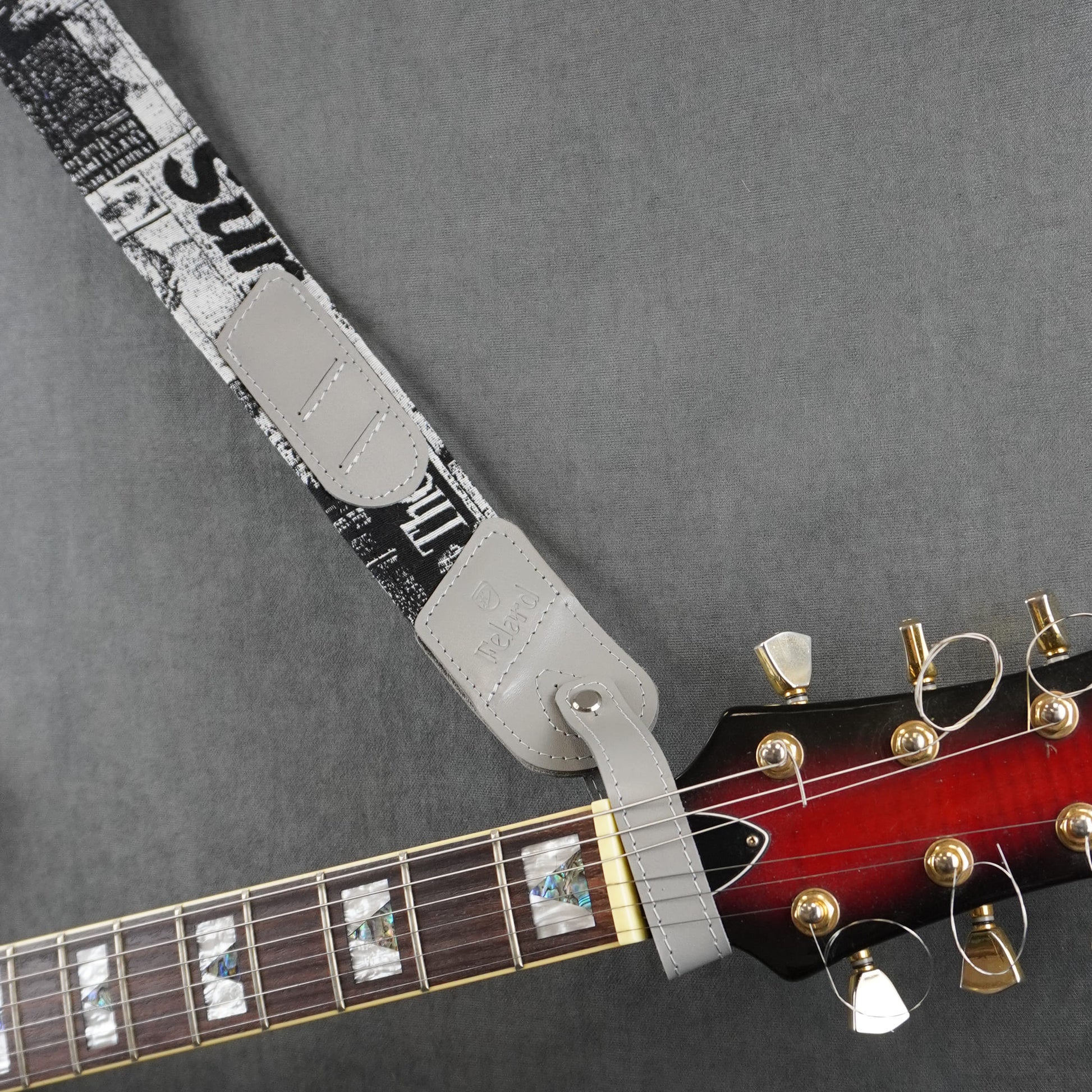 A guitar strap with fabric with gray smooth leather headstock adapter