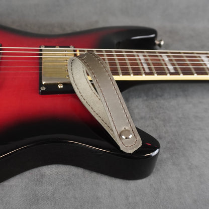A close-up of an electric guitar with a gray matte leather guitar headstock adapter