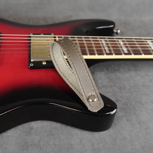 A close-up of an electric guitar with a gray matte leather guitar headstock adapter
