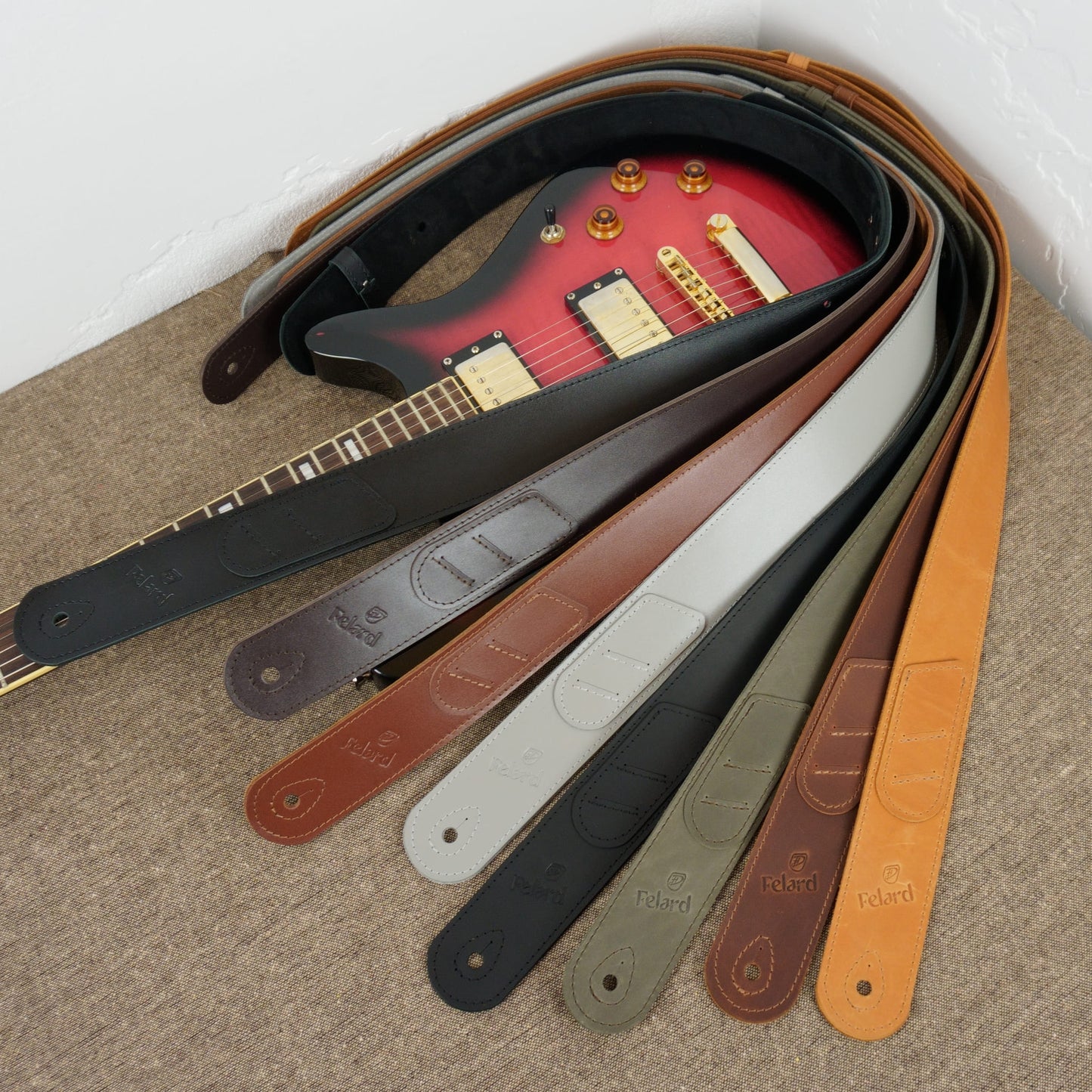 Genuine leather guitar strap color options by Felard displayed next to electric guitar