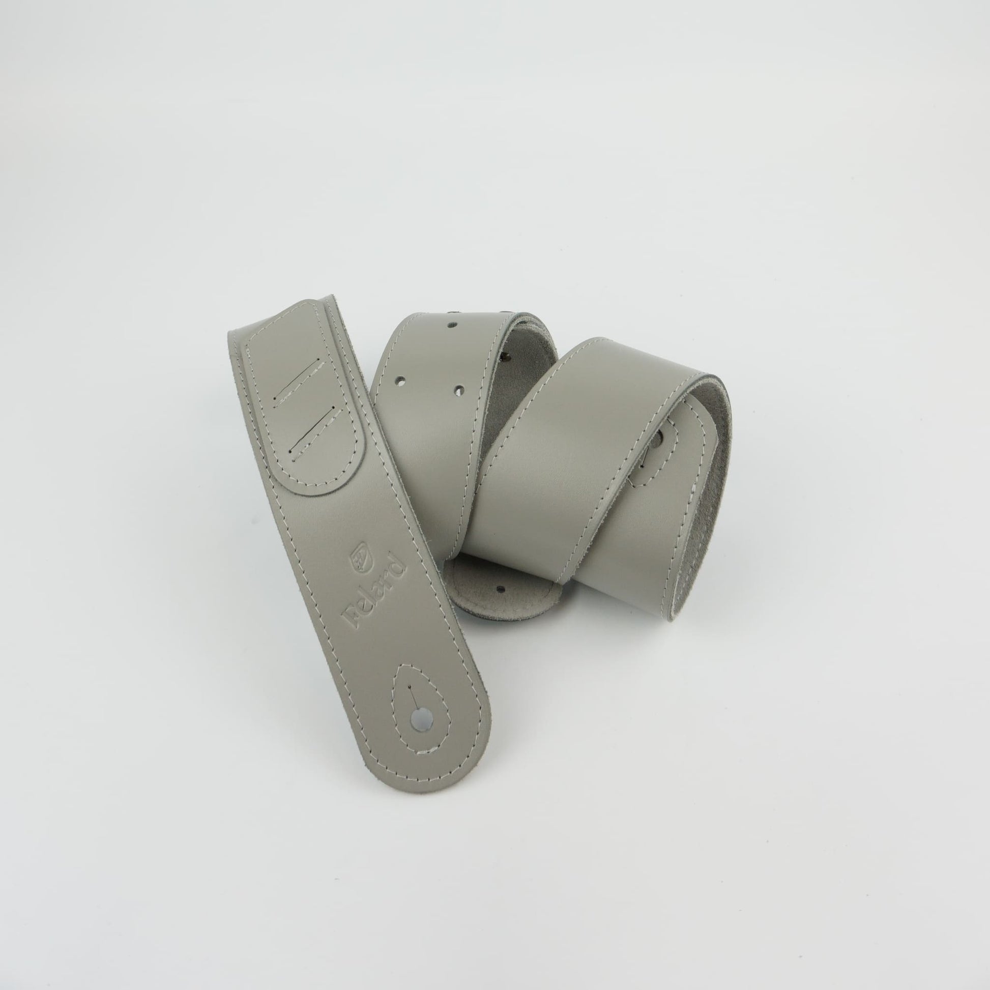 A light gray leather guitar strap coiled on a plain white background.
