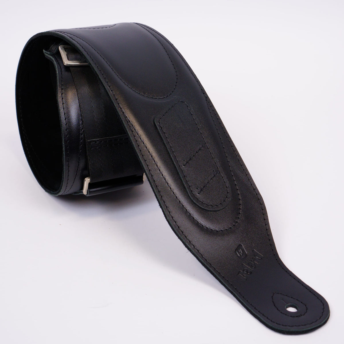 A black leather guitar strap with silver metal buckle, shown coiled on a white background.