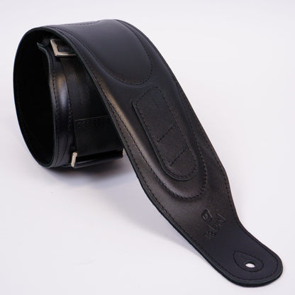 A black leather guitar strap with silver metal buckle, shown coiled on a white background.