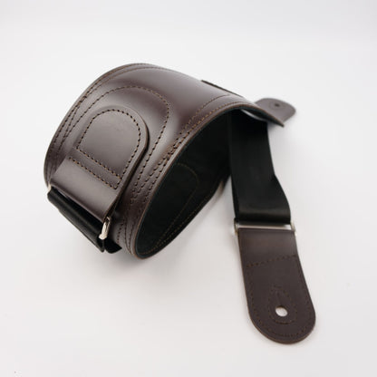 A dark brown leather guitar strap with a matching adjustable buckle, displayed on a clean white background.