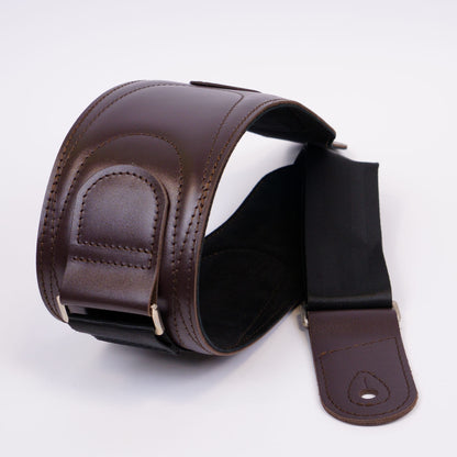 A dark brown leather guitar strap with a padded shoulder section, stitched edges, and a black adjustable webbing section, displayed on a clean white background.